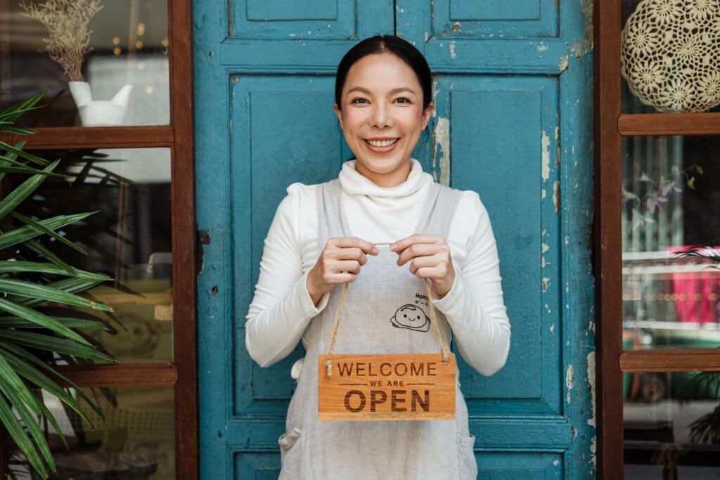 Woman sole proprietor holding open sign